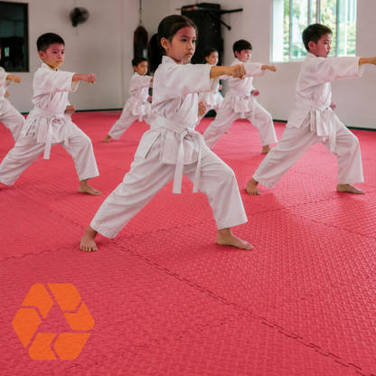 Niños practicando artes marciales sobre piso de goma EVA rojo de 4 cm de espesor con diseño de tatami modular.