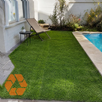 Pasto sintético verde de 15mm instalado junto a una piscina, resistente a rayos UV, ecológico y de alta calidad.